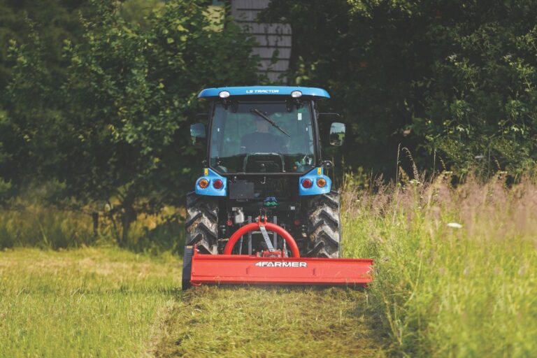 LS Traktor mit Kabine und Heckmulcher beim Mähen von hohem Gras